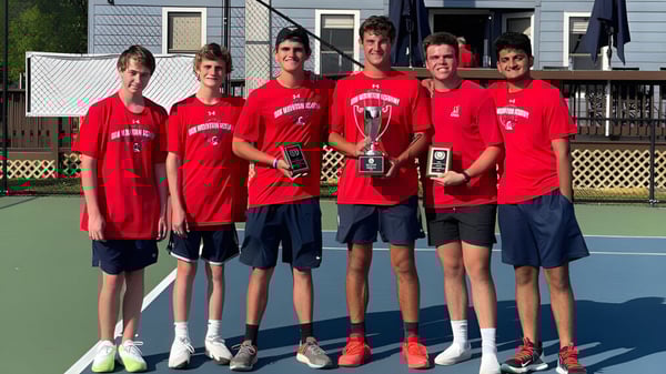 Un grupo de estudiantes de la Oak Mountain Academy está en la cancha de tenis sosteniendo trofeos.