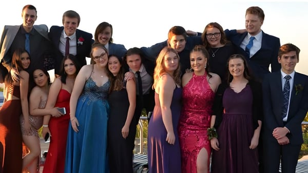 Un grupo de personas bien vestidas está junto a un paisaje en el terreno de la Oakbank Area School.