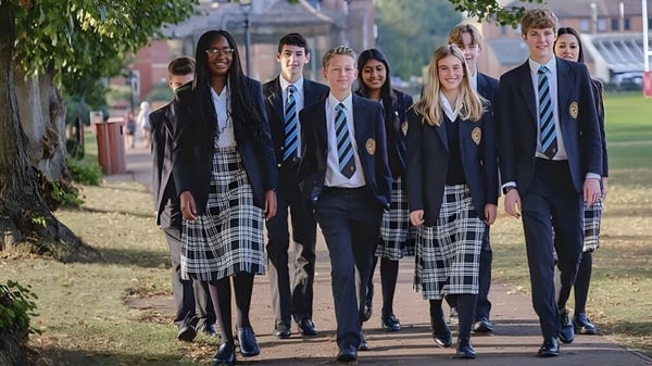 Un grupo de estudiantes de la Oakham School camina juntos por un camino rodeado de árboles y vegetación.