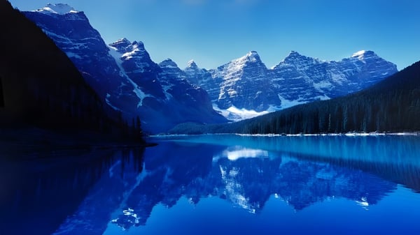 Un claro lago alpino refleja las montañas nevadas en los alrededores de la Oakridge Secondary School.