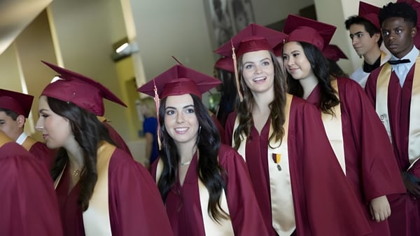 Un grupo de graduados de la Oaks Christian School en togas rojas están juntos en el pasillo celebrando su graduación.