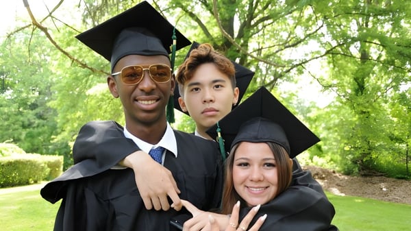 Tres graduados de la Oakwood Friends School posan juntos en el área verde exterior.
