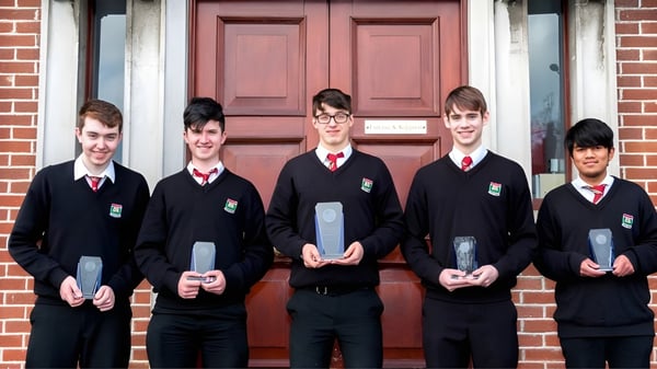 Un grupo de cinco alumnos en uniforme escolar está frente a una puerta de madera roja en el recinto del Oatlands College.