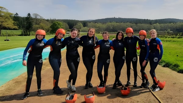 Estudiantes del O’Carolan College llevan trajes de neopreno y cascos en una actividad de deportes acuáticos al aire libre.
