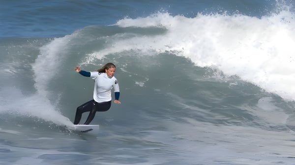 Un surfista monta una gran ola en el océano frente a un cielo nublado en el Odenz Programm.