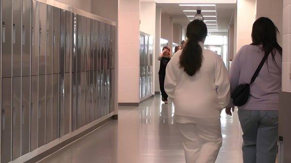 Los estudiantes caminan por el pasillo con taquillas en la pared de la Ohpaho Secondary School.