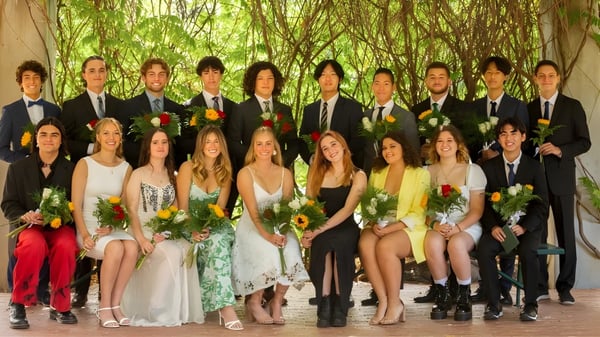 Un grupo de personas vestidas de gala posan en el campo en el terreno de la Ojai Valley School.