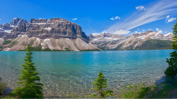 Vista de un lago alpino con montañas cubiertas de nieve y árboles de coníferas cerca de la Okanagan Mission Secondary School.