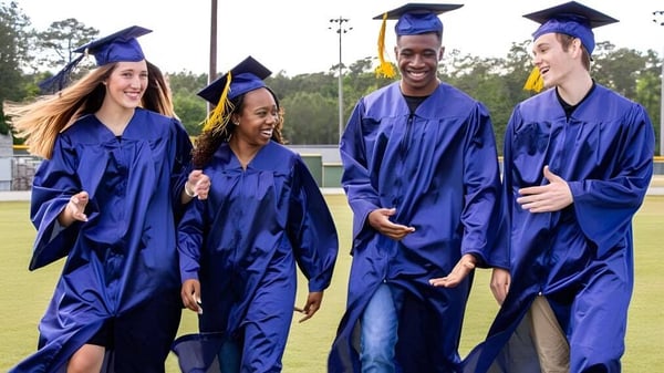 Cuatro graduados de Onslow College posan juntos en un prado frente a unos árboles.
