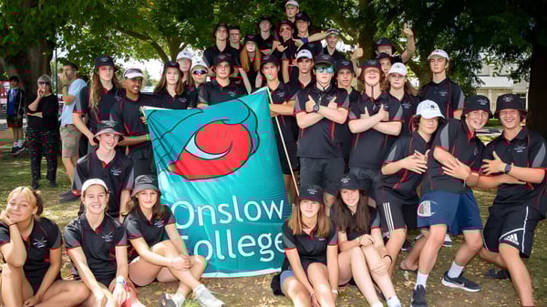 Un grupo de estudiantes de Onslow College está al aire libre sosteniendo una bandera con el nombre de la escuela.