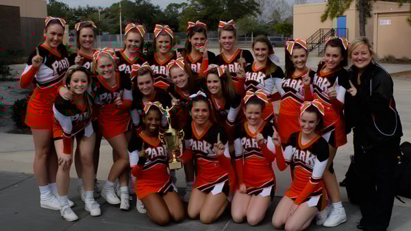 Estudiantes de las Orange County Public Schools posan con un trofeo frente a un edificio.