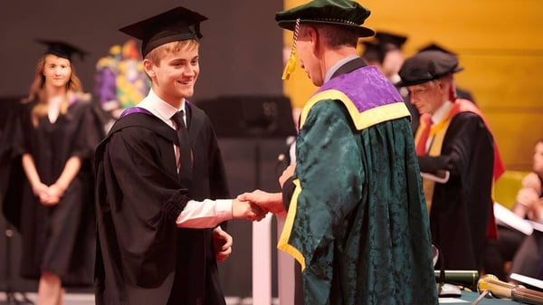 Dos graduados en togas se dan la mano en la ceremonia de graduación de la Orangeville District Secondary School.