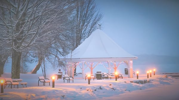 Un pabellón cubierto de nieve con faroles iluminados y sillas en el campus de la Orillia Secondary School en un paisaje invernal.