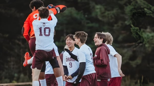 Un grupo de estudiantes de la Orono High School se reúne al aire libre frente a árboles y áreas verdes.