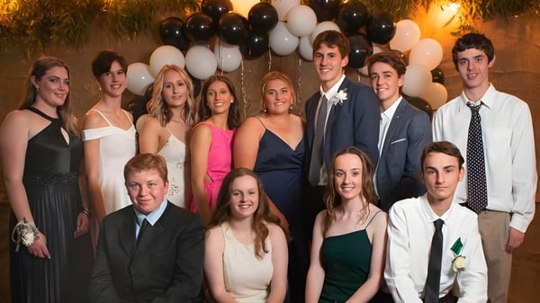 Un grupo de estudiantes de la Orroroo Area School posan frente a una decoración festiva en una celebración.
