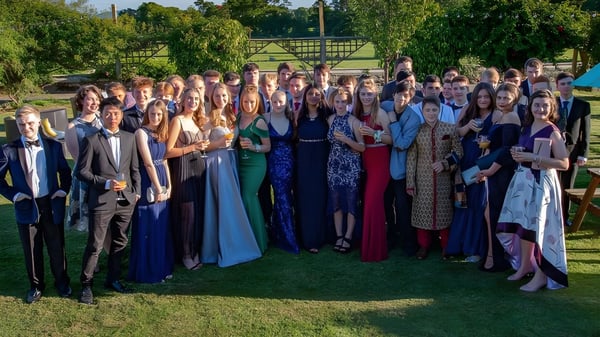 Un gran grupo de estudiantes vestidos formalmente está de pie en una pradera en el campus de la Oswestry School.