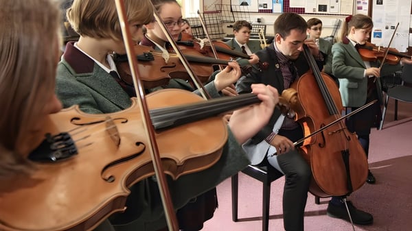 Un grupo de músicos de la Oswestry School ensaya juntos en una sala con instrumentos musicales.