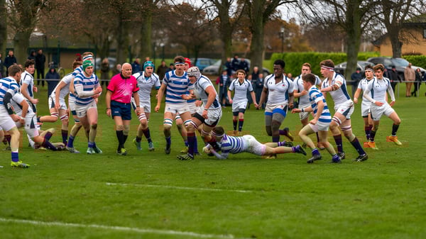 Un juego de rugby con jugadores en camisetas a rayas se lleva a cabo en el césped de Oundle School.