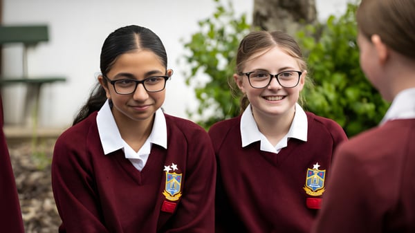 Dos estudiantes en uniforme escolar están en una pradera en el campus del Our Lady Catholic College.