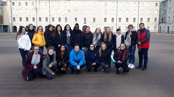 Un grupo de estudiantes se encuentra frente al gran edificio blanco de Our Lady's College.
