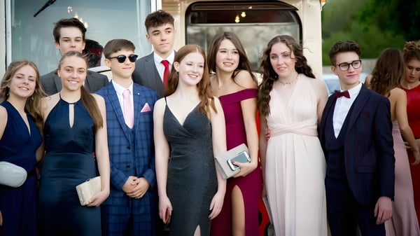 Un grupo de personas bien vestidas posan frente a un edificio en un evento en Our Lady’s Secondary School.