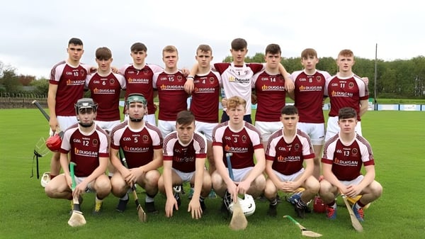 Un grupo de estudiantes en uniformes rojos y blancos posan en un campo deportivo en el terreno de Our Lady’s Secondary School.