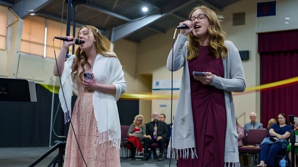 Dos estudiantes de las Overland Christian Schools cantan en el escenario durante una actuación.