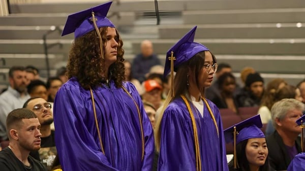 Un grupo de graduados en togas moradas se encuentra en el auditorio de las Overland Christian Schools.