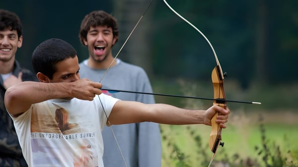 Estudiantes del Oxford International College Brighton practicando tiro con arco en un campo al aire libre.