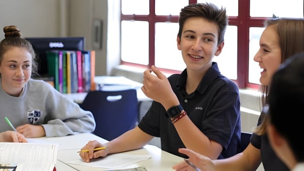 Tres estudiantes de la Pacifica Christian High School están conversando en un aula.