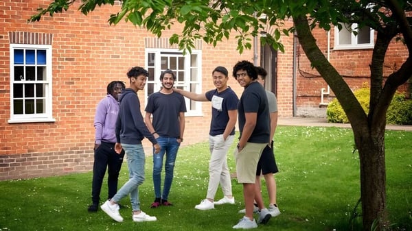Un grupo de estudiantes está de pie en un área verde frente a un edificio de ladrillo en el campus de Padworth College.