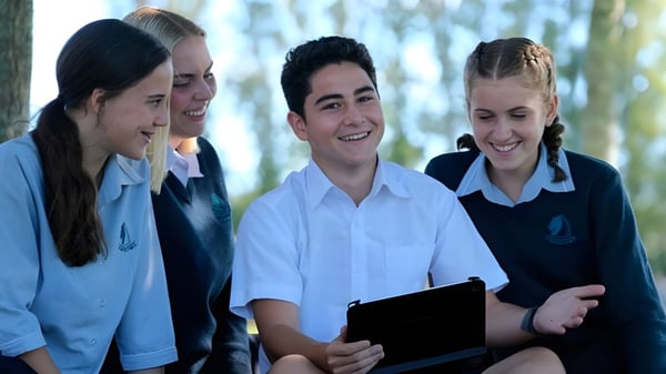 Un grupo de alumnos está juntos y sonríe al aire libre en el terreno del Pakuranga College.
