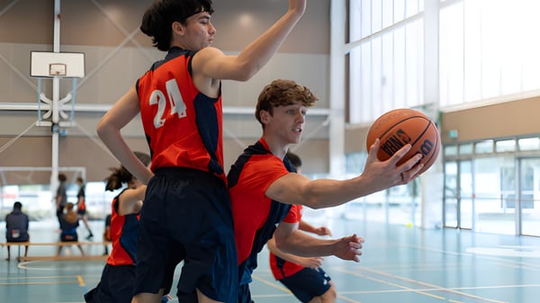 Dos jugadores de baloncesto luchan por el balón en la cancha del Papamoa College.