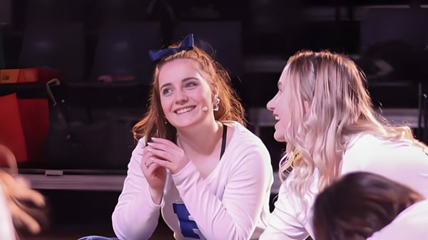 Dos estudiantes de Papanui High School están juntas en un escenario frente a un telón oscuro.