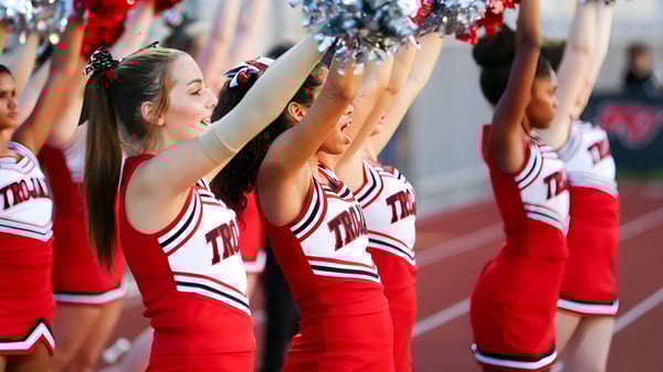 Un grupo de porristas del Paradise Valley Unified School District realiza una actuación en el campo deportivo frente a espectadores en el estadio.