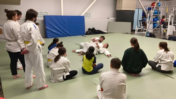 Un grupo de estudiantes de la Parkland Secondary School practica artes marciales juntos en una alfombra.