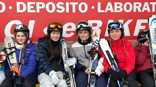 Estudiantes de la Patrician Presentation Secondary School están en equipo de esquí frente al letrero del Deposito Laborat Cheerkee.