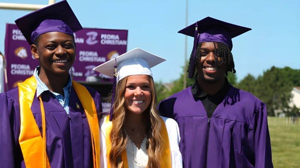 Tres graduados en togas moradas están frente a un fondo con el logo de la Peoria Christian School.