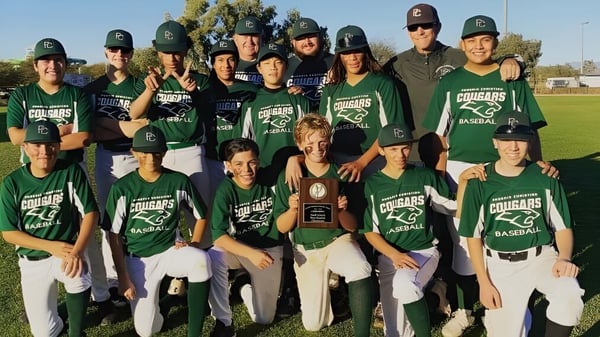 Estudiantes de la Phoenix Christian Preparatory School posan en uniformes de béisbol verdes juntos en el campo de béisbol.