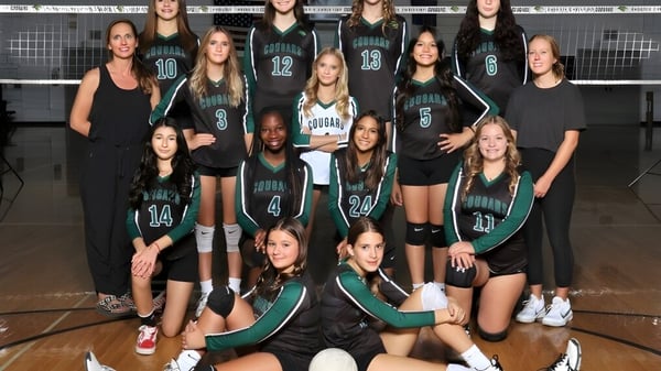 Un grupo de jóvenes jugadoras de voleibol posan en la cancha de voleibol de la Phoenix Christian Preparatory School.