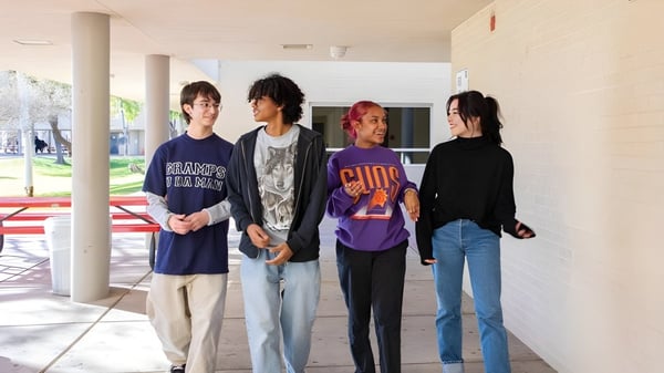 Un grupo de estudiantes está juntos al aire libre en el terreno de la Phoenix Union High School.