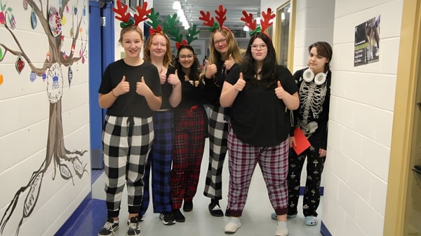 Un grupo de alumnas de la Picture Butte High School está reunido en el pasillo decorado festivamente.