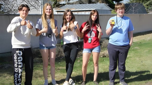 Un grupo de cinco alumnos está en el terreno de la Picture Butte High School frente a un edificio.