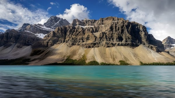 Vista de montañas cubiertas de nieve y un lago turquesa cerca de la Picture Butte High School.