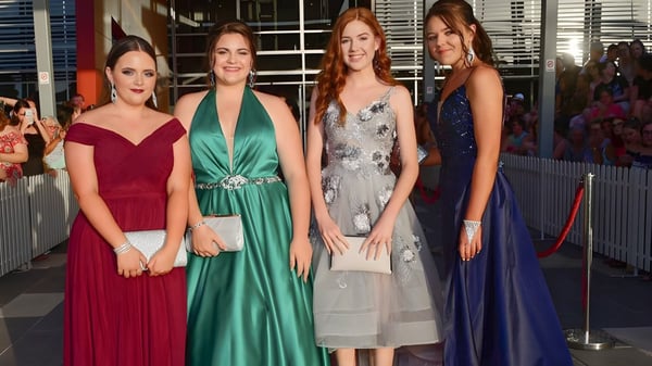 Cuatro estudiantes de la Pimlico State High School posan juntas en vestidos de gala sobre una alfombra roja.