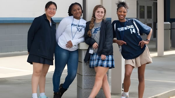 Cuatro estudiantes femeninas de la Pinewood Preparatory School están juntas al aire libre.