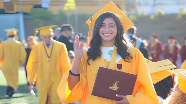 Una estudiante con toga de graduación amarilla sostiene un diploma durante la ceremonia de graduación en el Placentia-Yorba Linda Unified School District.