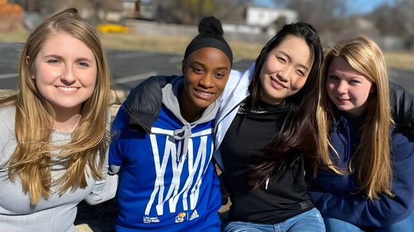 Cuatro estudiantes de la Plaza Heights Christian Academy están juntas afuera en un día soleado.