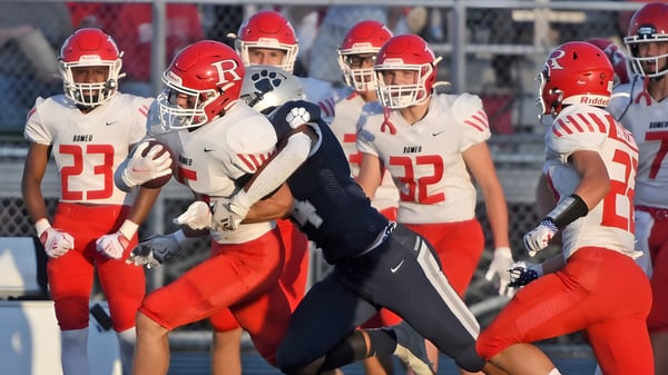 Un grupo de futbolistas en camisetas rojas está en el campo con un entrenador en el campus de la Plaza Heights Christian Academy.