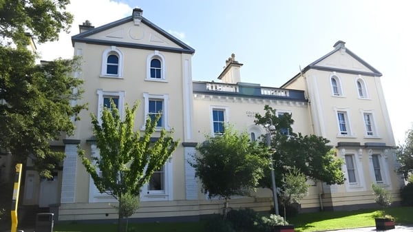 El edificio blanco de varios pisos con arquitectura elaborada en el terreno del Plymouth College está rodeado de árboles.